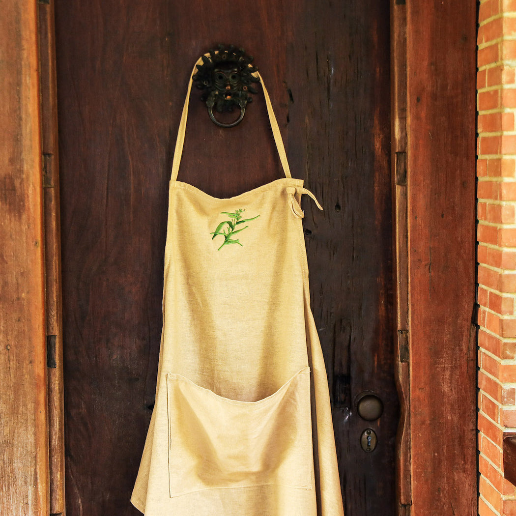 Keep your dress spiff while baking up a storm in this long linen apron, detailed with an intricately embroidered adlai plant to pay homage to our local indigenous crops. Wrap the straps all-around your waist to hold your kitchen towels, and use the handy front pocket to keep your phone or your thermometer in close reach. The neck strap loops into a hole to keep it adjustable for all family members! Lovingly made in the Philippines. Baking essentials available online through Domesticity.